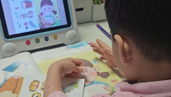 아이가 학습기와 교재를 오가며 스스로 학습하는 모습